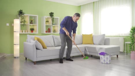 Middle-aged-man-doing-housework,-mopping-floors-in-living-room.
